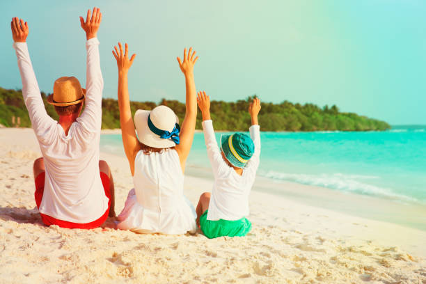 istock happy family with child hands up on beach 956316220