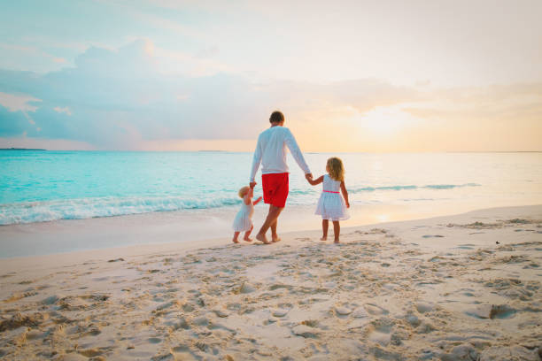 istock father with two kids walking on beach at sunset 956316636