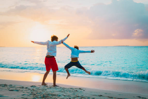 istock father and son have fun jump at sunset beach 956316744