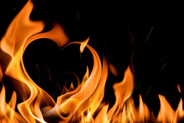 Black background with flames in the shape of a heart stock photo