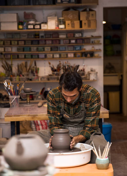 istock Male artist makes clay pottery on a spin wheel 956317670