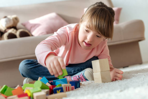 istock Kid with down syndrome playing with toy cubes 956318074