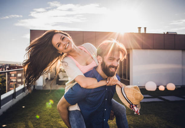 istock Happy couple having fun while piggybacking on a penthouse terrace. 956318096
