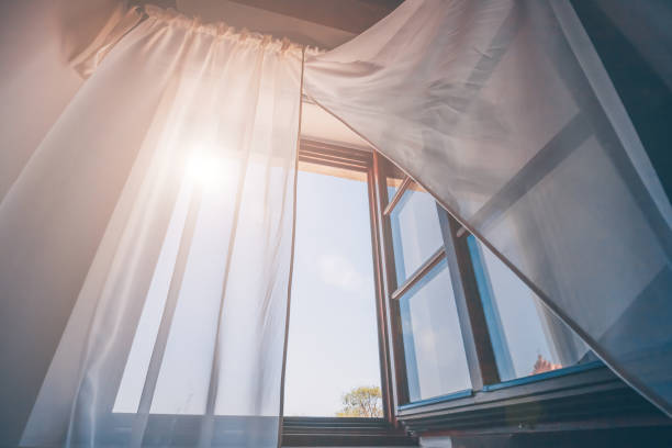 istock Bright morning sun in the open window through the curtains 956321856