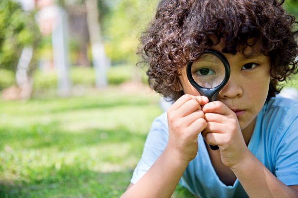 istock Little boy with magnifying glass in park 956322344