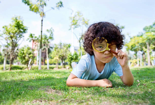 istock Little boy with magnifying glass in park 956322346