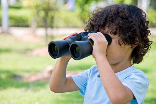 istock Little boy holding a binocular at park 956322520