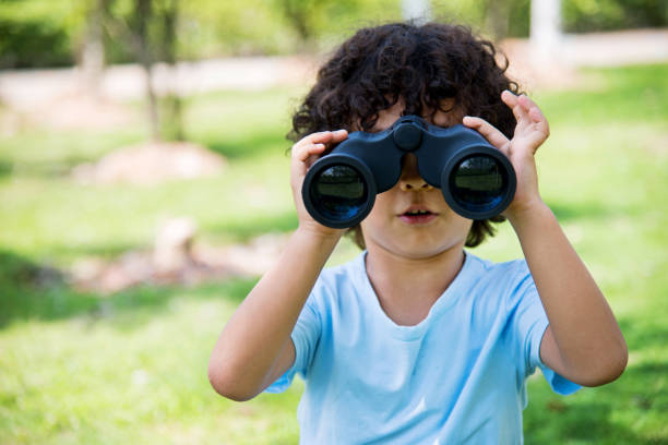 istock Little boy holding a binocular at park 956322570