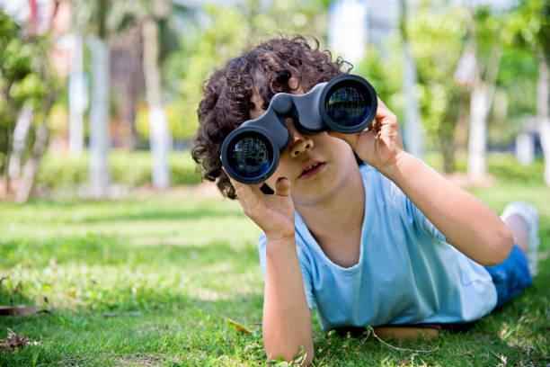istock Little boy holding a binocular at park 956322572