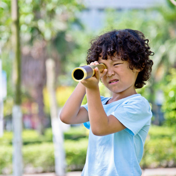 Little boy holding a telescope at park.