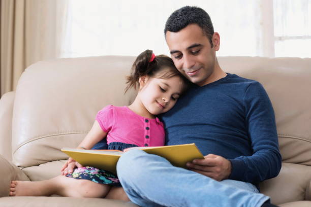 istock Little Girl And Father Reading Book 956322656