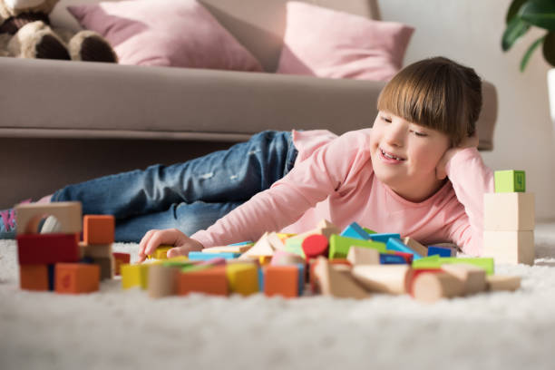 istock Kid with down syndrome lying on floor and looking at toy cubes 956325248