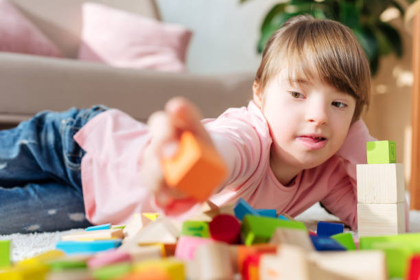 istock Kid with down syndrome building with toy cubes 956326864