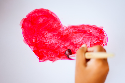 Child hand drawing and painted a heart for valentine's card with fun