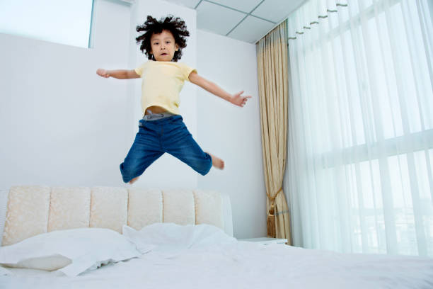 istock Little boy jumping on the bed 956329470
