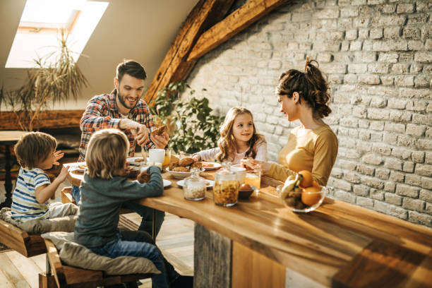 istock Young happy parents enjoying with their kids during breakfast time at dining table. 956330912