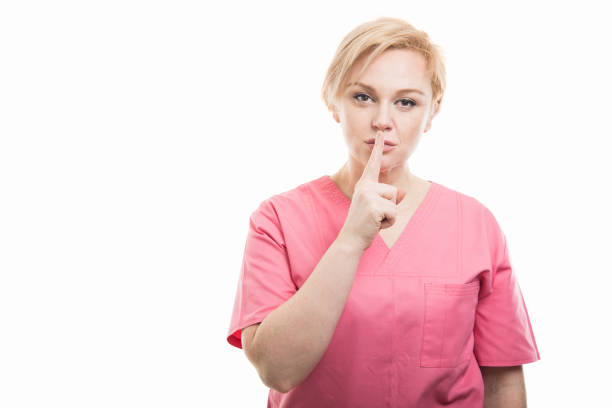 istock Attractive female nurse wearing pink scrubs making silent gesture 956331386