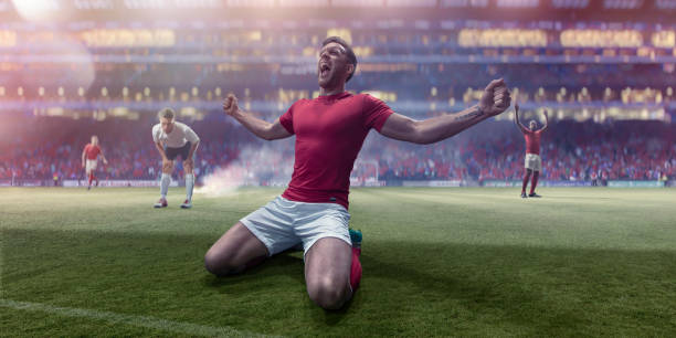 istock Kneeling Professional Soccer Player Shouting With Arms Out In Celebration 956335868
