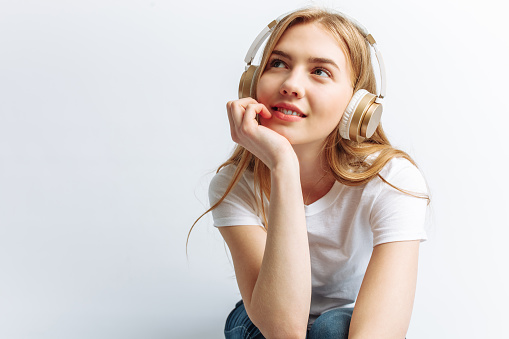 Girl listening to music through large headphones, and sitting at the laptop, photo Studio