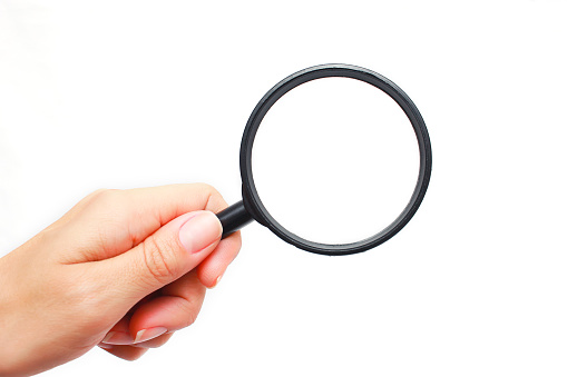 Female hand with a magnifying glass on a white background