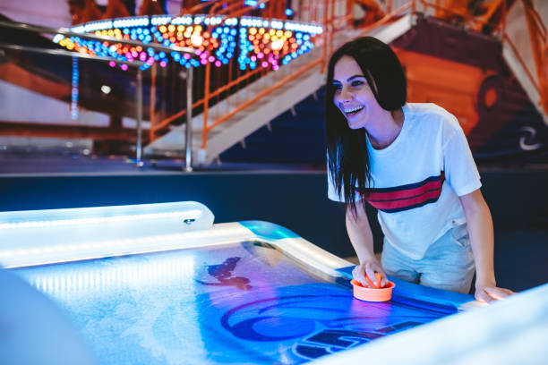 Having fun in amusement park Attractive young woman is having fun in amusement park. Playing table hockey. arcade photos stock pictures, royalty-free photos & images