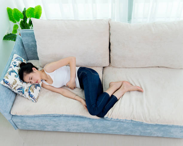 istock Young woman having stomachache on sofa 956357476