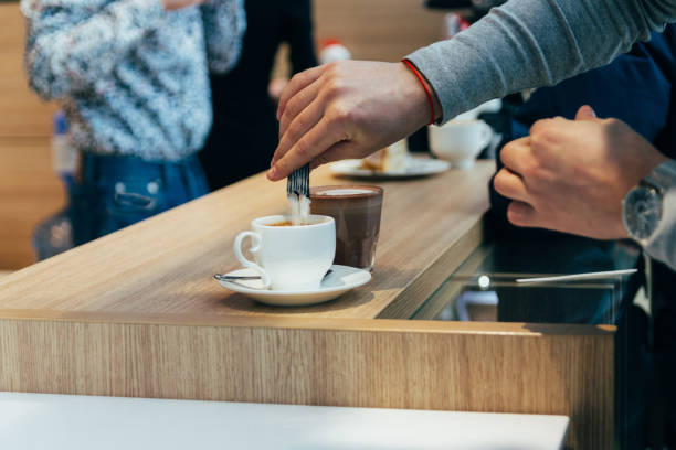 mann die hände gießen zucker zum latte cup im café - sugar sachet stock-fotos und bilder