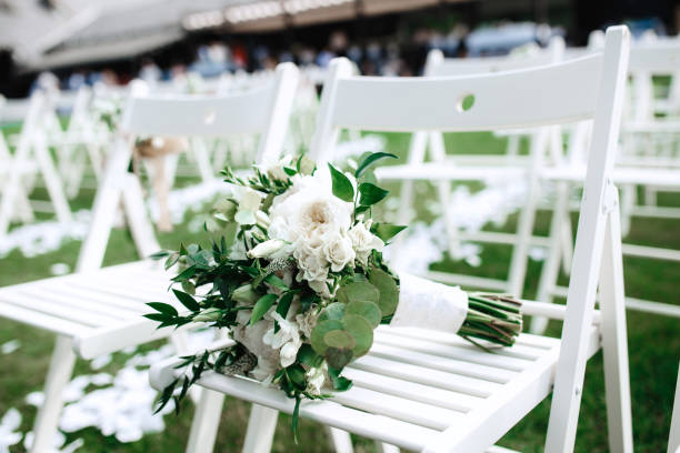 istock Wedding bouquet of white roses on the white chairs. 956367126