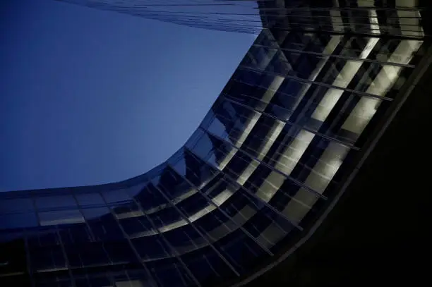 Futuristic office building at night, blue toned image. These buildings have offices from different companies and are situated next to the center of city.