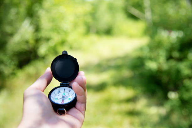 Hand holding a compass outdoors.