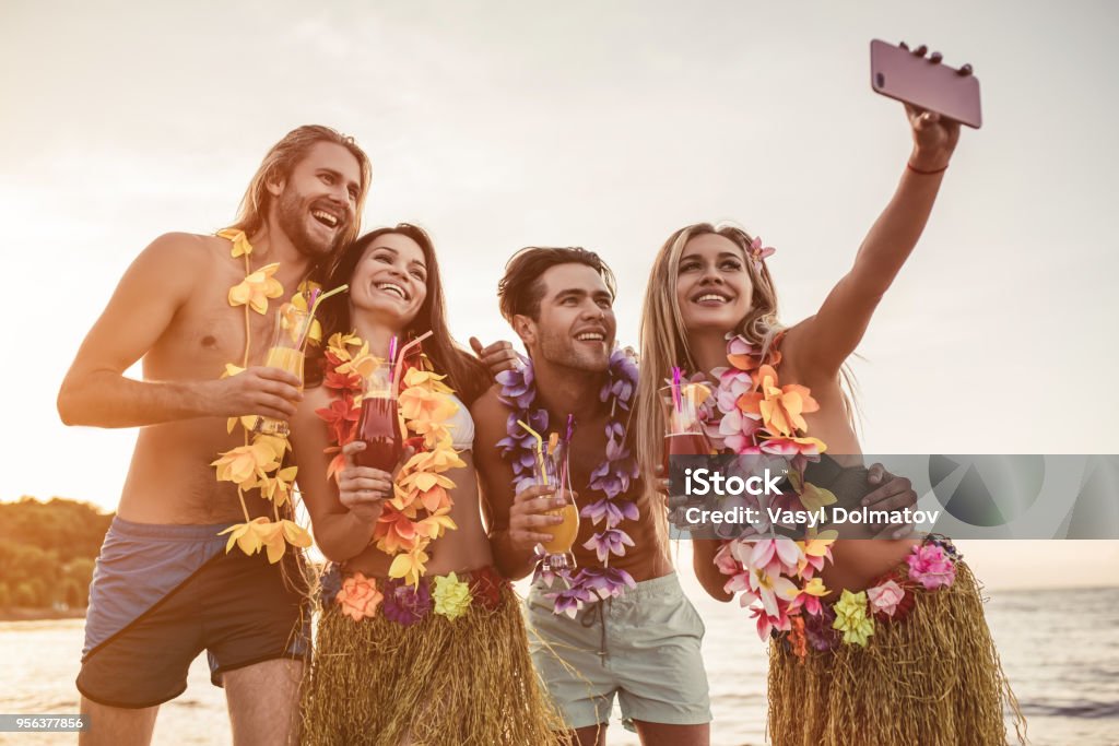 Group of friends on beach Group of young attractive friends are having fun on beach, smiling and making selfie. Party in Hawaiian style. Hawaii Islands Stock Photo