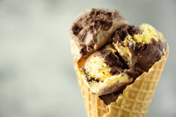 istock Chocolate and coffee ice cream in waffle cone with coffee beans on grey stone background. Summer food concept, copy space. Healthy gluten free ice-cream 956378584