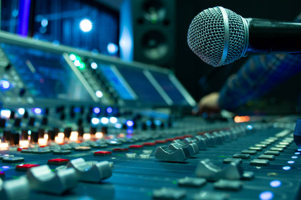 istock Professional condenser studio microphone over the abstract photo blurred of Hand adjusting audio mixer, Musical instrument Concept 956383548