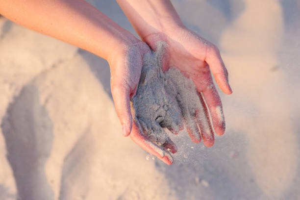 istock female hands pour sand on the ground 956386736