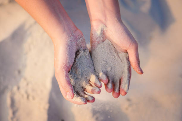 istock female hands pour sand on the ground 956386764