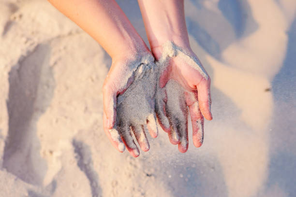 istock female hands pour sand on the ground 956386780
