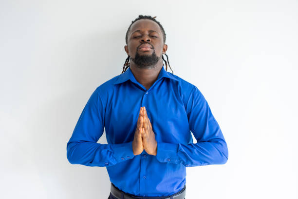 istock Calm concentrated black guy holding hands together in Namaste 956391926