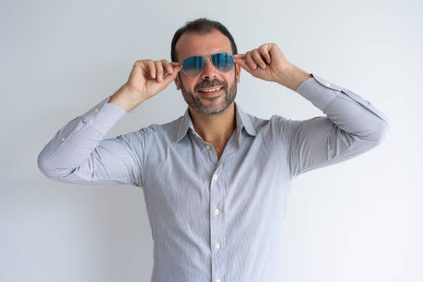 Positive handsome middle-aged Latin man putting on sunglasses. Cheerful relaxed handsome man adjusting glasses. Dreaming about vacation concept