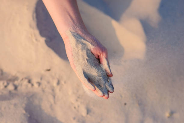 istock female hands pour sand on the ground 956396088