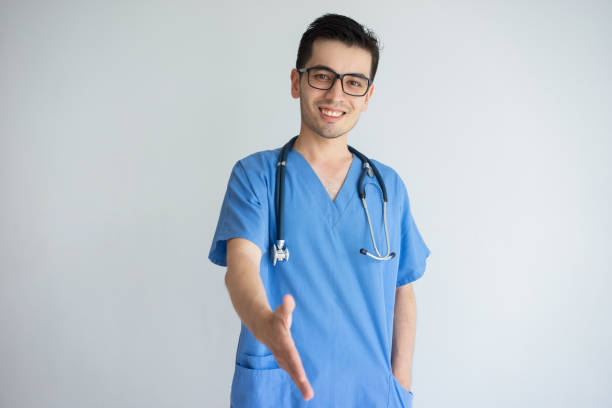 istock Smiling young male doctor offering hand for handshake 956400822