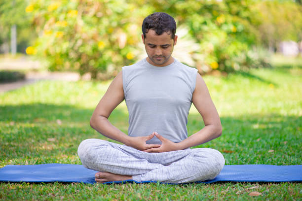 istock Focused Indian guy doing yoga asanas in park 956402898