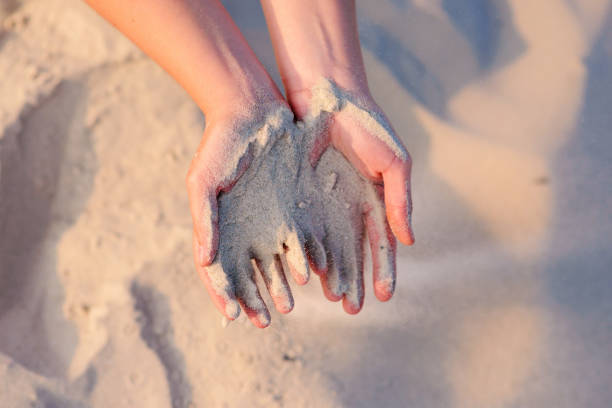 istock female hands pour sand on the ground 956403912