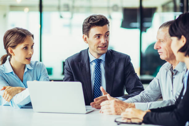istock Four Business People Discussing Project at Desk 956415246