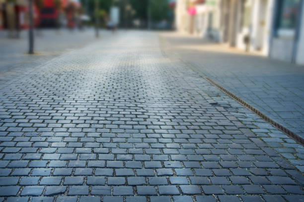 istock Cobbled stone road early morning with reflection of light 956420354