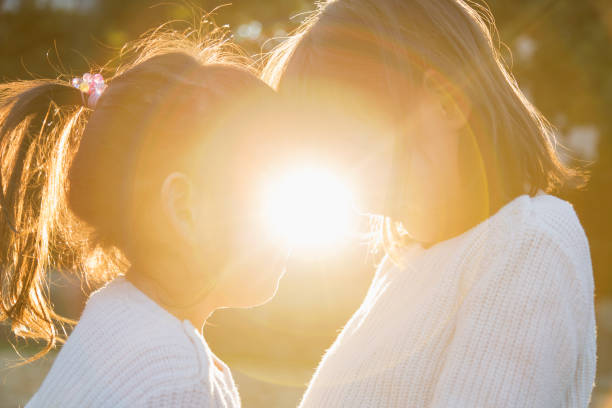 istock Sisters putting heads together and smiling outside with backlight 956421134