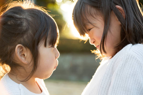 istock Sisters enjoying staring-out game outside with backlight 956421172