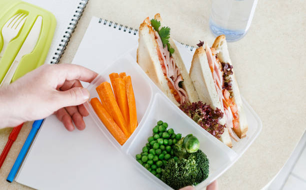 père se prépare un repas scolaire sur la table de cuisine à domicile. boîtes à lunch école avec sandwich et légumes frais, bouteille d’eau. concept de la saine alimentation - packed lunch sandwich school lunch turkey photos et images de collection