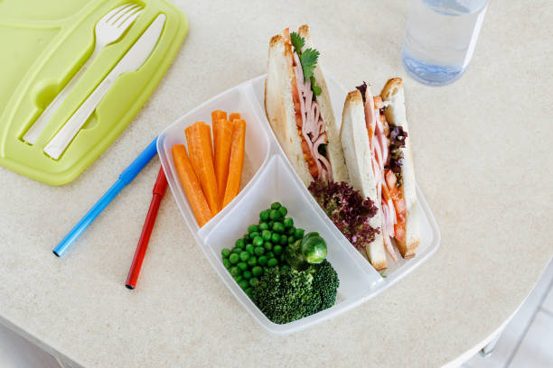 boîtes à lunch santé scolaire avec sandwich et légumes frais, bouteille d’eau sur la table de cuisine à domicile. concept de la saine alimentation - packed lunch sandwich school lunch turkey photos et images de collection
