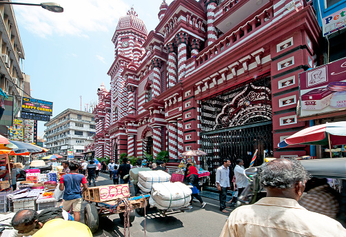 Pettah market area with traditional market barrows in front of the distinctive candy-striped Red Mosque, or Red Masjid in 2nd Cross Street, Fort, Colombo, Sri Lanka