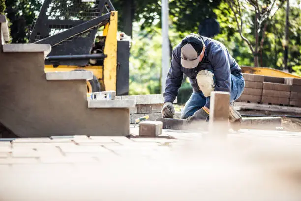 Photo of Senior man installing paving stones in front of his house